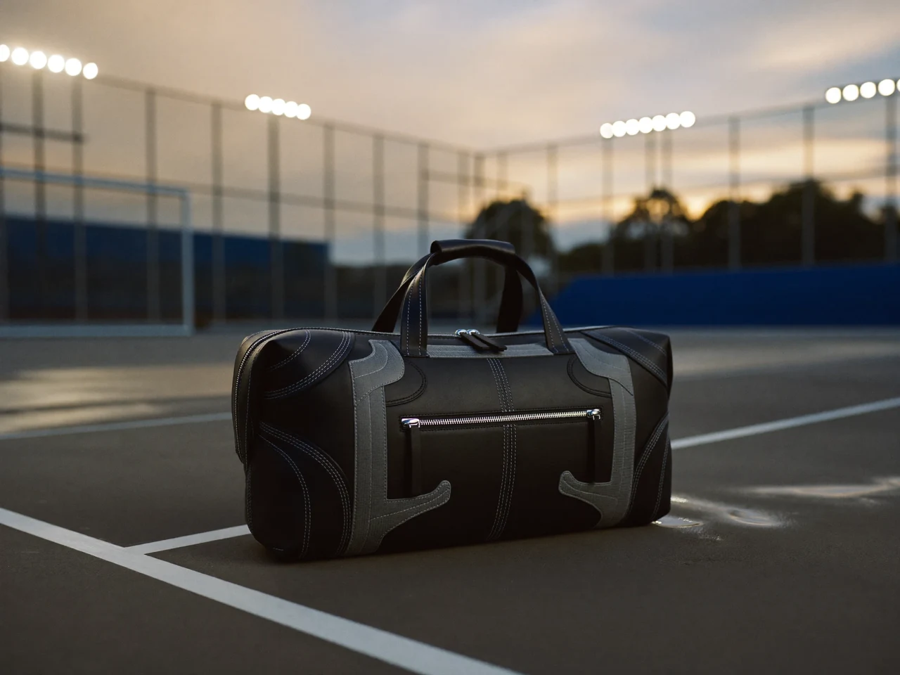 Un sac de sport posé sur le béton mouillé d'un terrain urbain au crépuscule