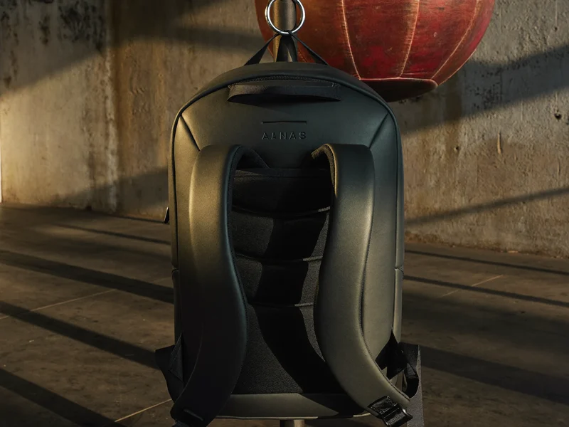 Sac à dos d'entraînement anthracite suspendu à un crochet près d'un sac de frappe